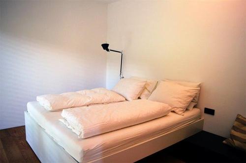 a bed with white sheets and a lamp on it at Weingut Bachgütl in Cermes