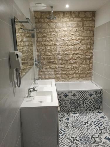 une salle de bain avec un lavabo et un mur en pierre dans l'établissement Château des Loups - Les Cyprès, à Échiré