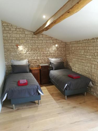 - 2 lits dans une chambre avec un mur en pierre dans l'établissement Château des Loups - Les Cyprès, à Échiré