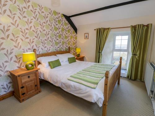 ein Schlafzimmer mit einem großen Bett und einem Fenster in der Unterkunft The Stable Cottage in Llanbedr