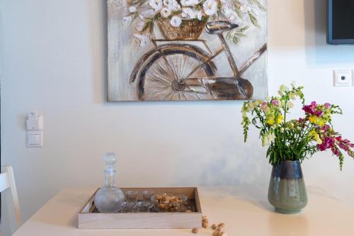 a table with a vase of flowers and a painting at Cretan Minoan Apartments in Zákros