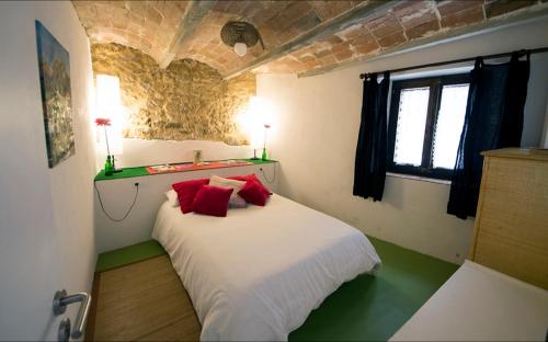 Un dormitorio con una cama con almohadas rojas. en Ca la Teia, en Bellcaire dʼEmpordà