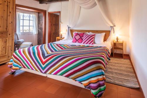a bed that has a blanket and pillows on it at Aldeia da Cuada in Faja Grande