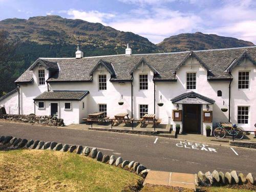 a white inn with mountains in the background at Whistlefield Inn in Dunoon