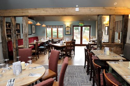 a dining room with wooden tables and chairs at White Hart by Chef & Brewer Collection in Chalfont Saint Giles