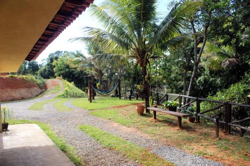 a park with a bench and a hammock and palm trees at Pousada Nova Gironda in Paty do Alferes