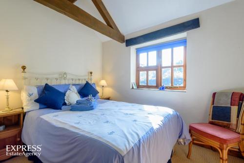 a bedroom with a bed with blue pillows and a window at Highgrove Barns in Craven Arms