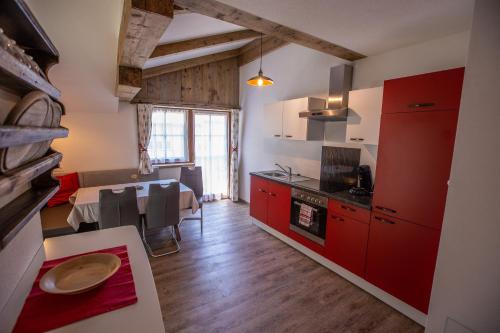 a kitchen with red cabinets and a dining table at Ferienwohnung Heimatglück in Matrei in Osttirol