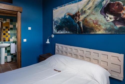 1 dormitorio con 1 cama con una pintura en la pared en Las Casitas de la Data en Gallegos