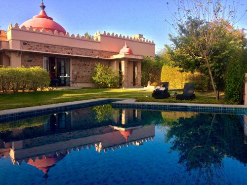 a man sitting on a chair next to a swimming pool at Tree of Life Resort & Spa Jaipur in Jaipur