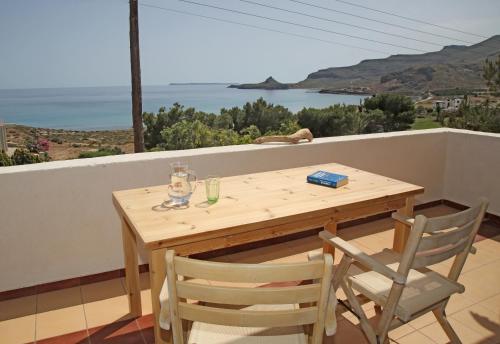 a wooden table and chairs on a balcony with a view of the ocean at Aqua Bliss in Xerokampos