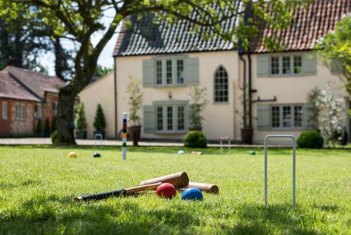 a bunch of baseball equipment in the grass in front of a house at Holly Lodge Boutique B&B in Thursford