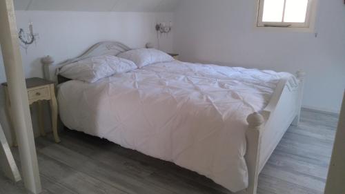 a white bed in a bedroom with a wooden floor at B&B Het mooie uitzicht in Reuver