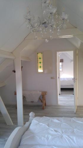 a white bedroom with a bed and a chandelier at B&B Het mooie uitzicht in Reuver