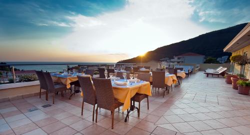 un restaurante con mesas y sillas en un balcón en Hotel WGrand, en Petrovac na Moru