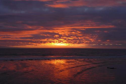 a sunset on a beach with the ocean at Les Chambres des Gites des Isles in Barneville-Carteret