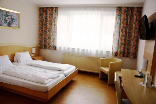 a hotel room with a bed and a desk and a window at Gasthaus & Gästehaus Bsteh in Wulzeshofen