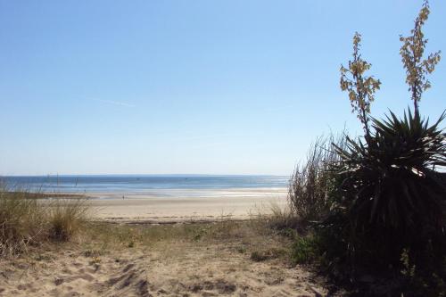 a sandy beach with a view of the ocean at Les Chambres des Gites des Isles in Barneville-Carteret