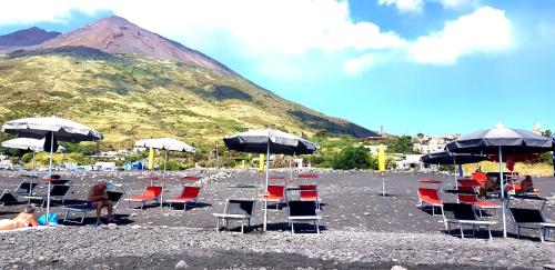 a group of chairs and umbrellas on a beach at Villa Mareblu Luxury Holiday Apartment direttamente sul mare in Stromboli