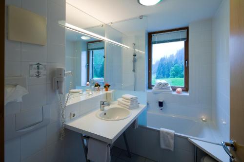 a white bathroom with a sink and a mirror at Widderstein Apartments in Schröcken