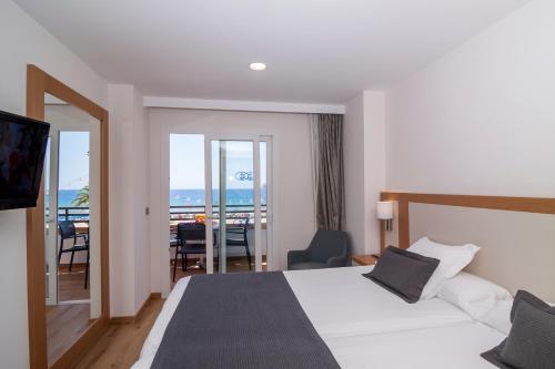 a hotel room with a bed and a view of the ocean at Les Dunes Comodoro in Benidorm