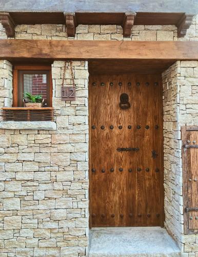 ColungoにあるAntiguo Rincónの窓付きの石造りの建物の木製ドア