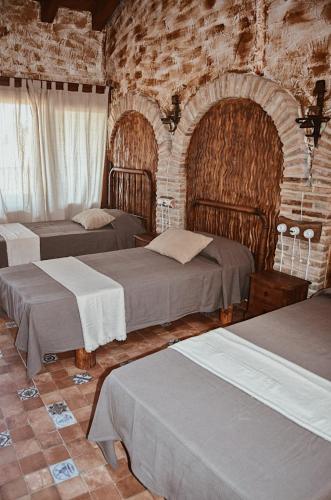 een slaapkamer met 3 bedden en een bakstenen muur bij Antiguo Rincón in Colungo