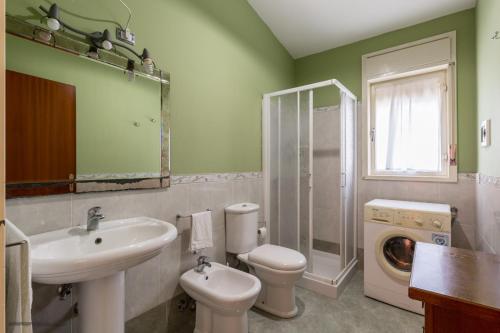 La salle de bains est pourvue d'un lavabo, de toilettes et d'un lave-linge. dans l'établissement Irene's house near the sea with pool, parking & wi-fi, à Avola
