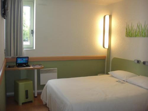 a bedroom with a bed and a desk with a laptop at ibis budget Châtellerault Nord in Châtellerault