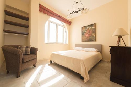 a bedroom with a bed and a chair and a window at Villa Arokaria in Stení