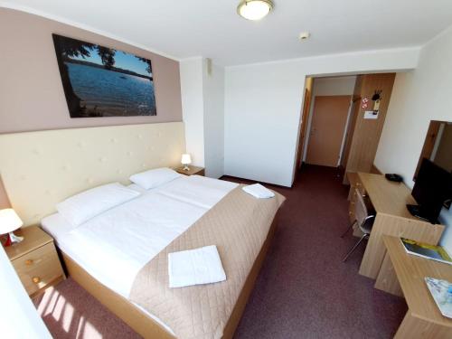 a bedroom with a bed and a desk and a television at Hotel Mazuria Country & SPA in Mrągowo