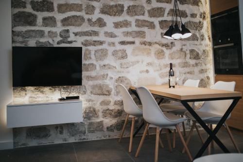 a dining room with a table and a tv on a stone wall at Apartments Trifunovic Old Town in Budva