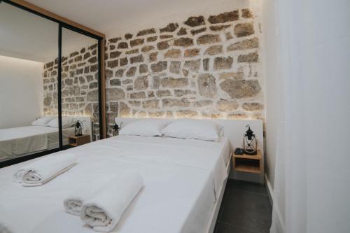 a bedroom with a white bed and a stone wall at Apartments Trifunovic Old Town in Budva