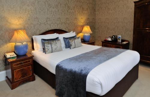 A bed or beds in a room at Best Western PLUS Grim's Dyke Hotel 