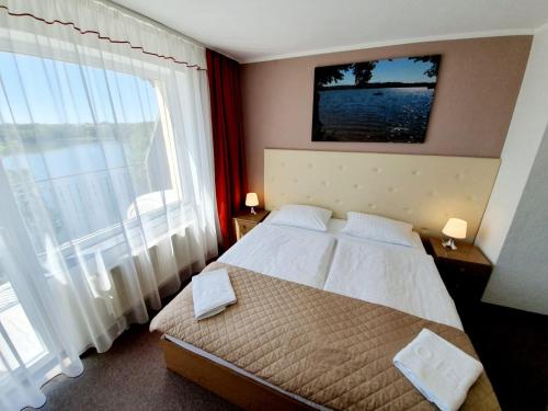 a bedroom with a bed and a large window at Hotel Mazuria Country & SPA in Mrągowo