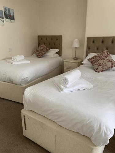 two beds in a hotel room with white sheets at The Queens Head in Stratford-upon-Avon