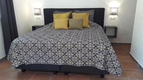 1 cama con edredón blanco y negro y almohadas amarillas en Finca Roca Vista, en Alhaurín el Grande