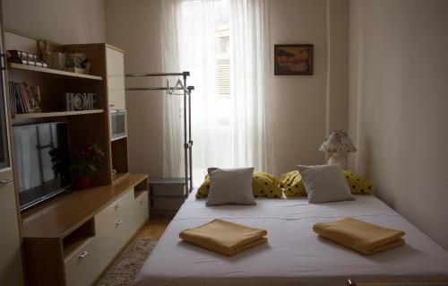um quarto com uma cama com almofadas amarelas e uma televisão em Apartman Sofija em Zadar