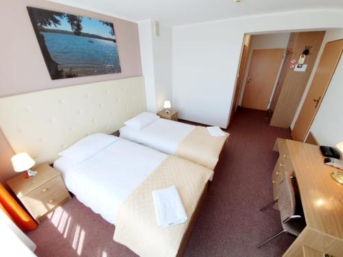 a hotel room with two beds and a desk at Hotel Mazuria Country & SPA in Mrągowo