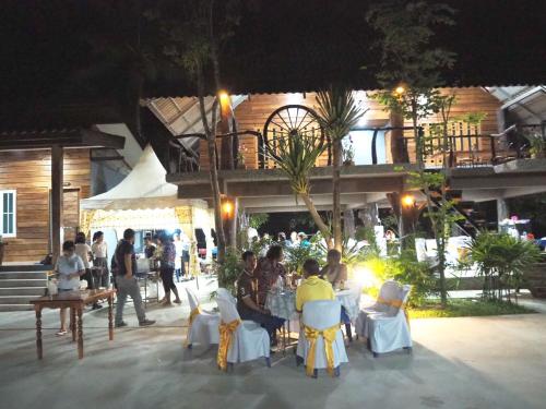 a group of people sitting at tables in front of a building at Nao Ta Chuang in Thung Song