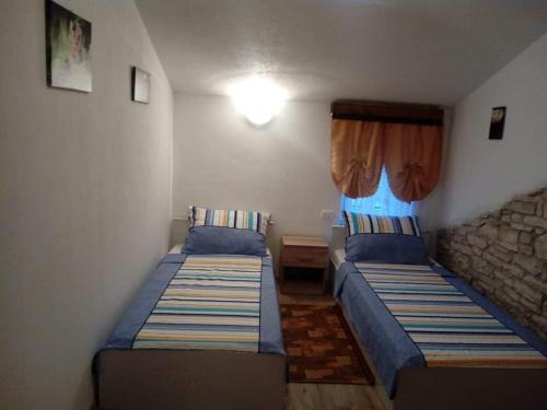 two beds in a small bedroom with a window at APP GAŠI in Buje
