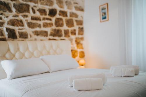 a bedroom with a white bed with a stone wall at Apartments Trifunovic Old Town in Budva