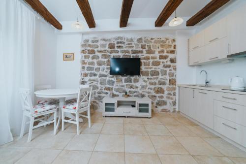 a kitchen with a table and a tv on a brick wall at Apartments Trifunovic Old Town in Budva