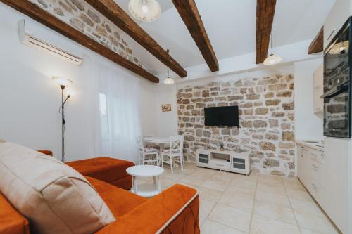 a living room with a couch and a tv on a brick wall at Apartments Trifunovic Old Town in Budva