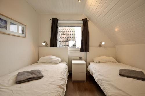 twee bedden in een kleine kamer met een raam bij Ferienwohnung Leuchtturmblick in Wangerooge