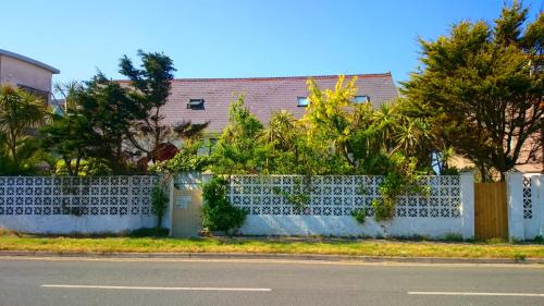 a white fence with plants on the side of a street at The Blue Palms - Fistral Beach in Newquay