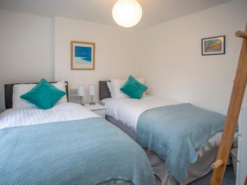 duas camas num quarto com lençóis verdes e brancos em Bryn Teg Cottage em Menai Bridge