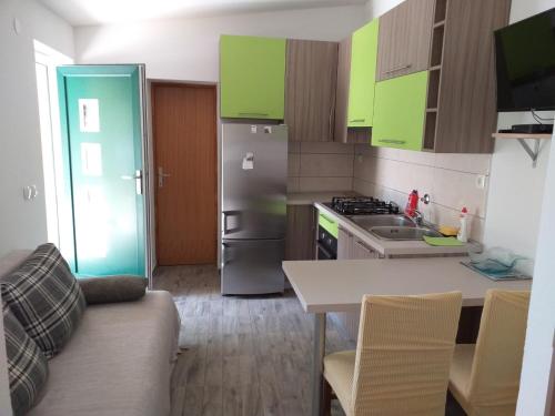 a kitchen with green cabinets and a table and a refrigerator at Apartments Uvala Murtar in Jezera