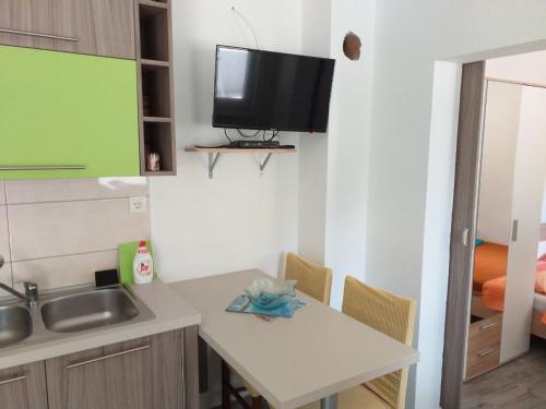 a small kitchen with a table and a tv on the wall at Apartments Uvala Murtar in Jezera