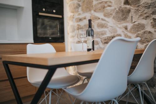 a wooden table with white chairs and a wine glass at Apartments Trifunovic Old Town in Budva